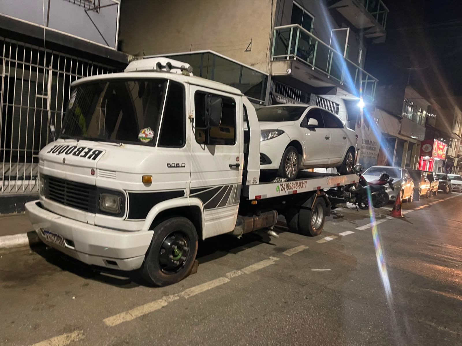 Caminhão-guincho realizando reboque de carro à noite