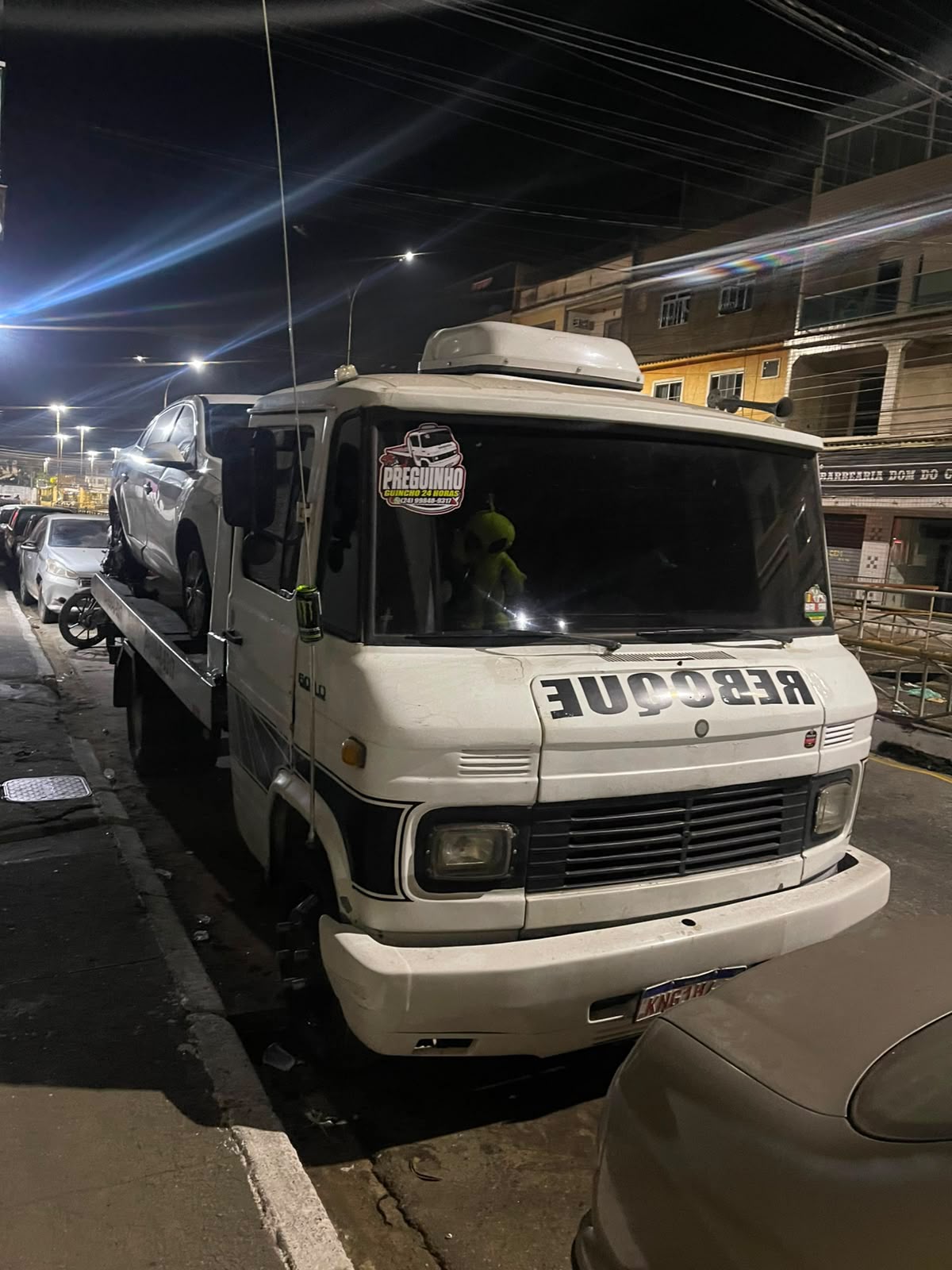 Guincho rebocando carro à noite em via urbana